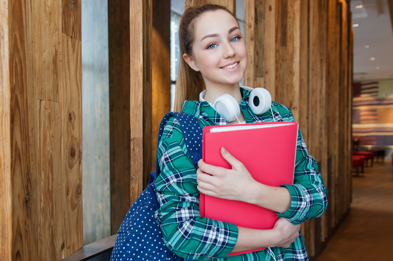 a university student smiling and holding a book